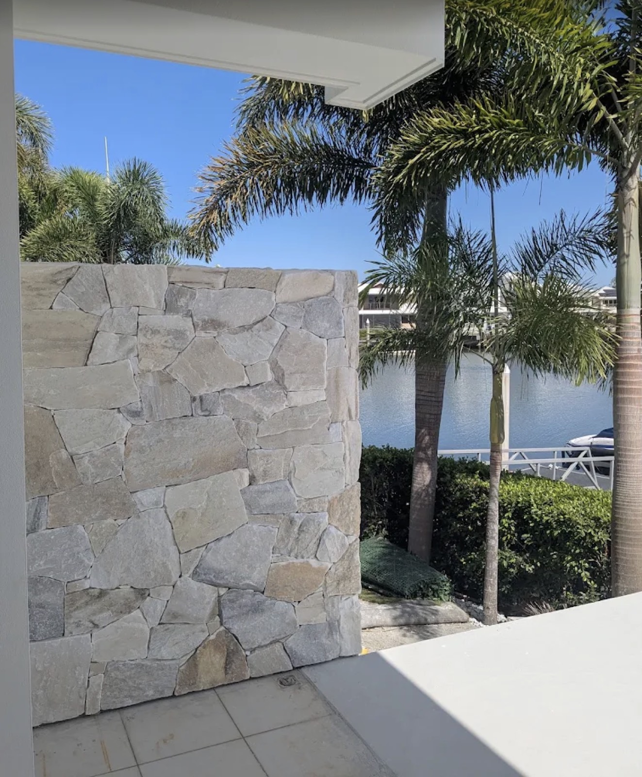 Sandstone feature wall beside palm trees on the waterfront