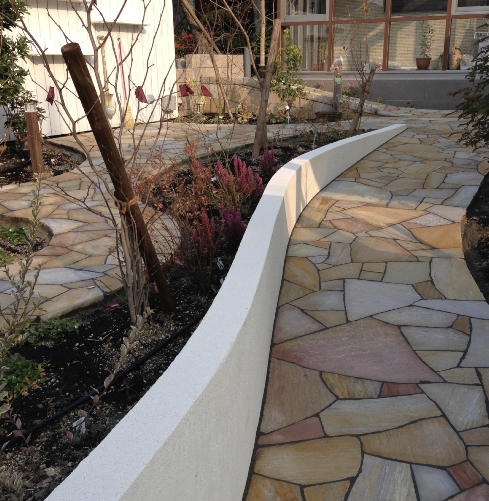 Curved rendered wall with natural flagstone crazy paving