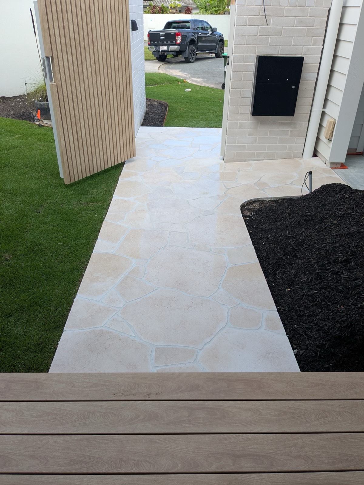 White crazy paving path between new turf and mulched garden beds